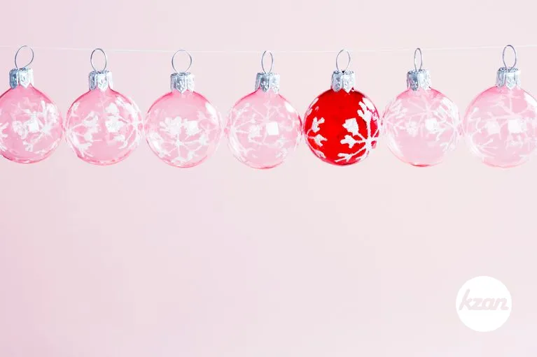Chistmas balls hanging next to each other on a line, with a red ball standing out from the rest.