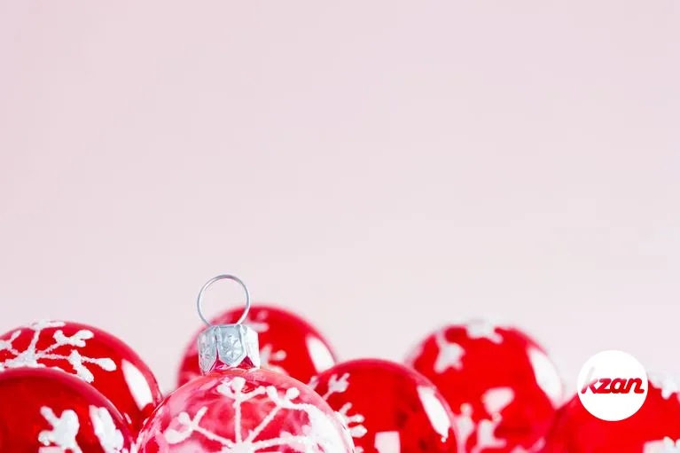 Christmas ornament balls framed against a pink plain background.