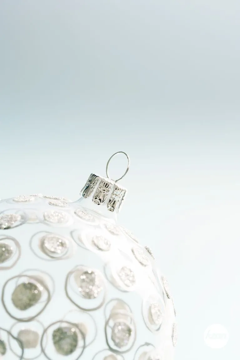 Close up detailf of a Christmas ball ornament against a soft blue background.