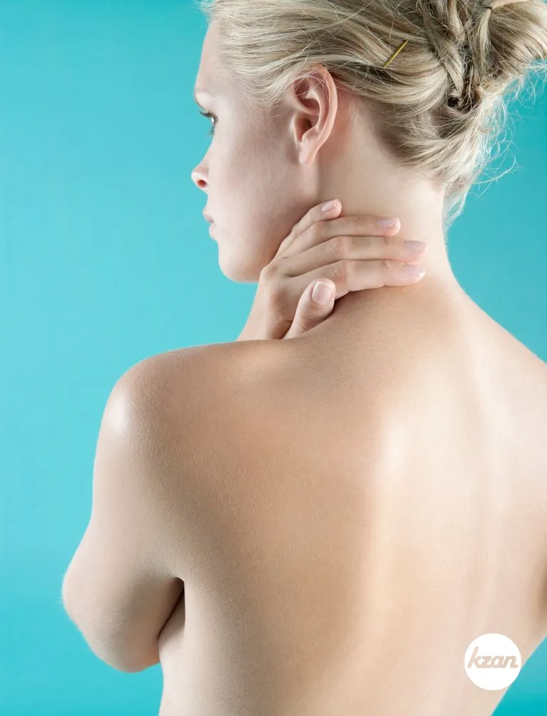 Close up view of a woman's bare back with her hand on her neck.