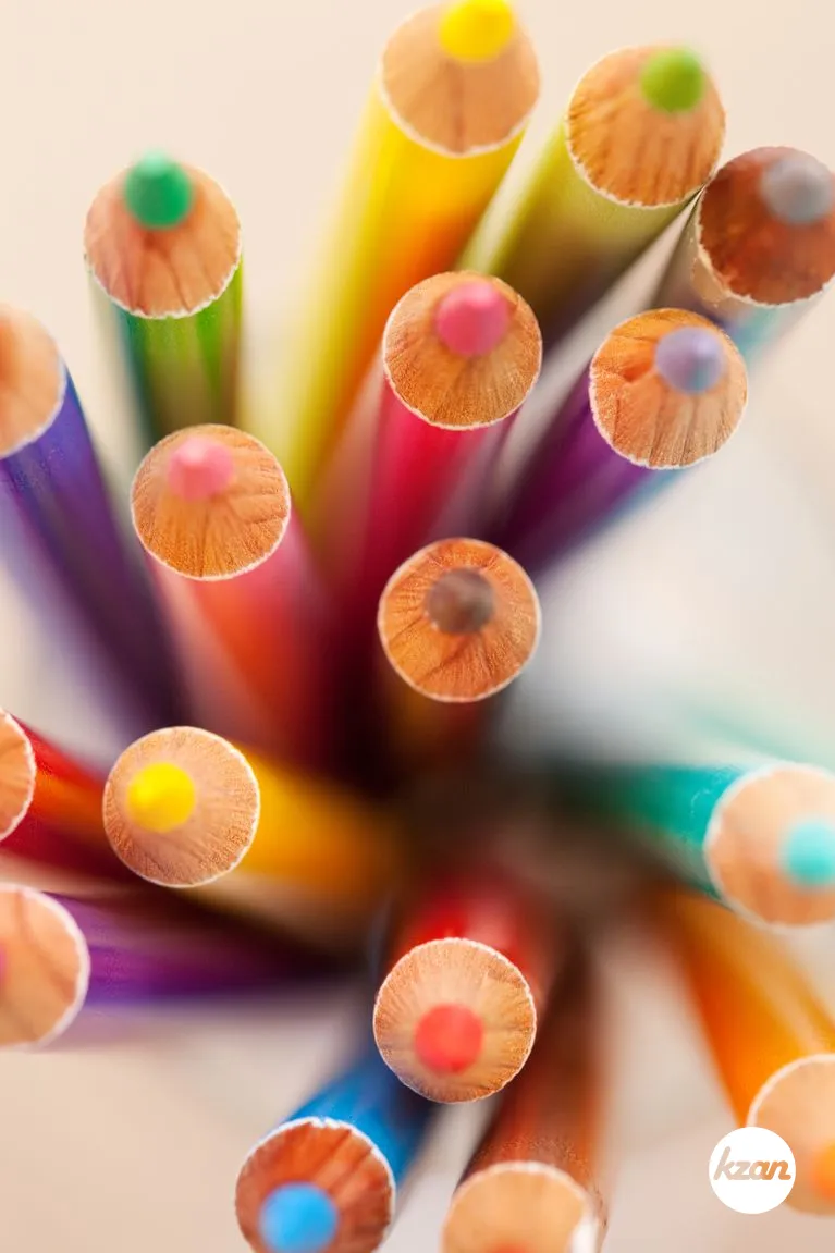 Over head close up view of a bunch of multiple colored drawing pencils isolated on a plain background.