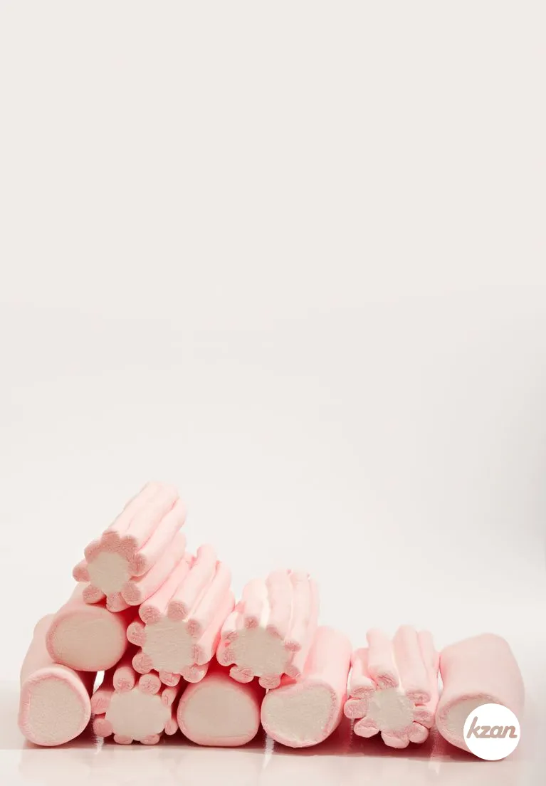 Still life view of a line of candy sweet marshmallows isolated against a white background, interior. Indulging and tempting sugar full foods and kids party celebration. Sweet tooth eating.