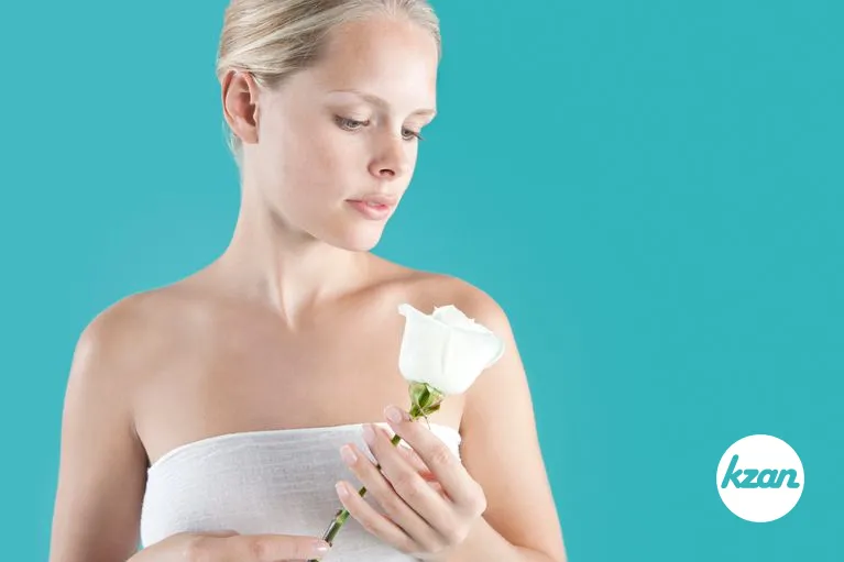 Young blonde woman holding a white rose in her hands.